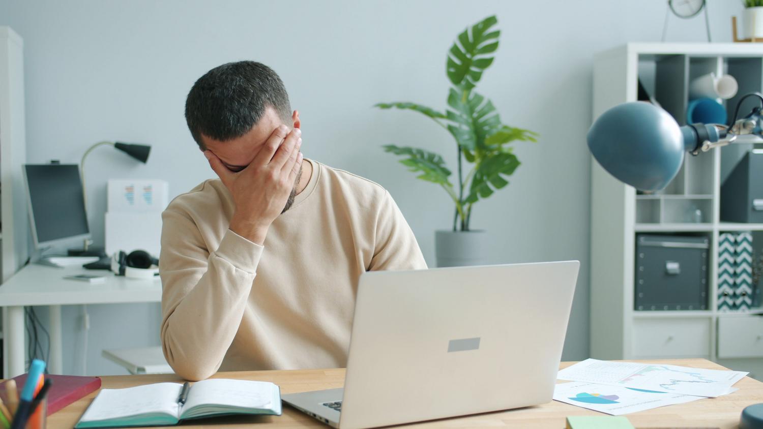 Hombre trabajador abrumado y frustrado en su escritorio, ilustrando la dificultad de resolver errores técnicos de software y códecs.