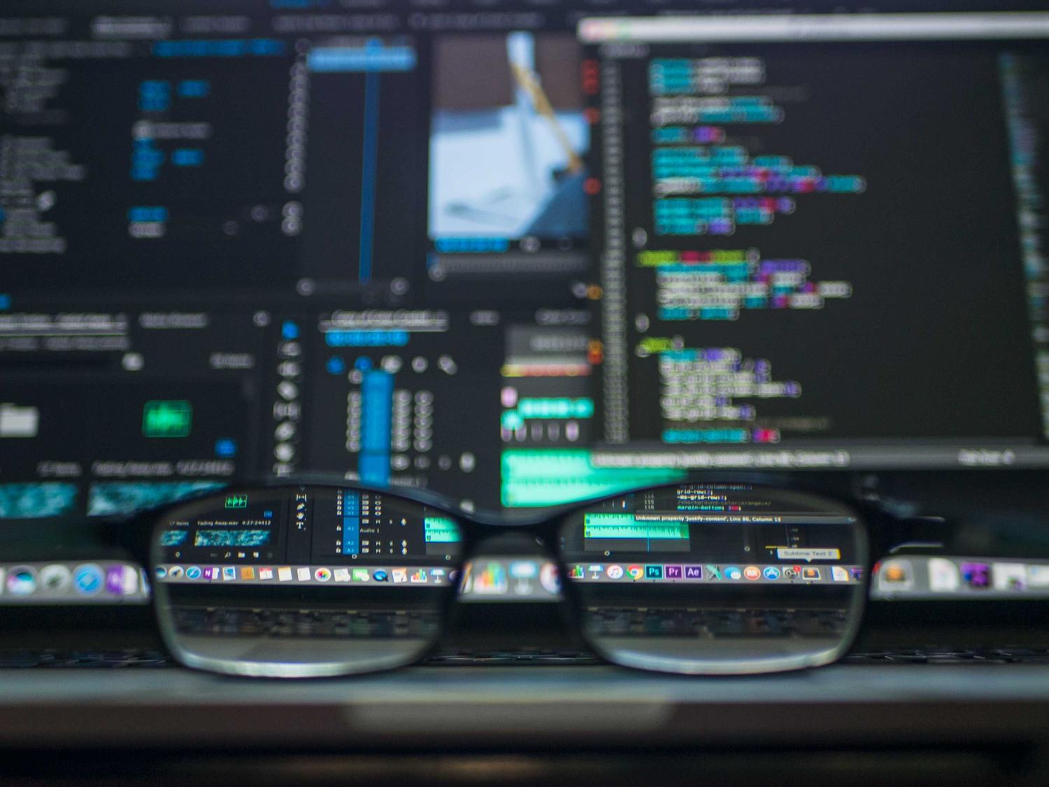 Reflejo de código en unas gafas frente a una pantalla.