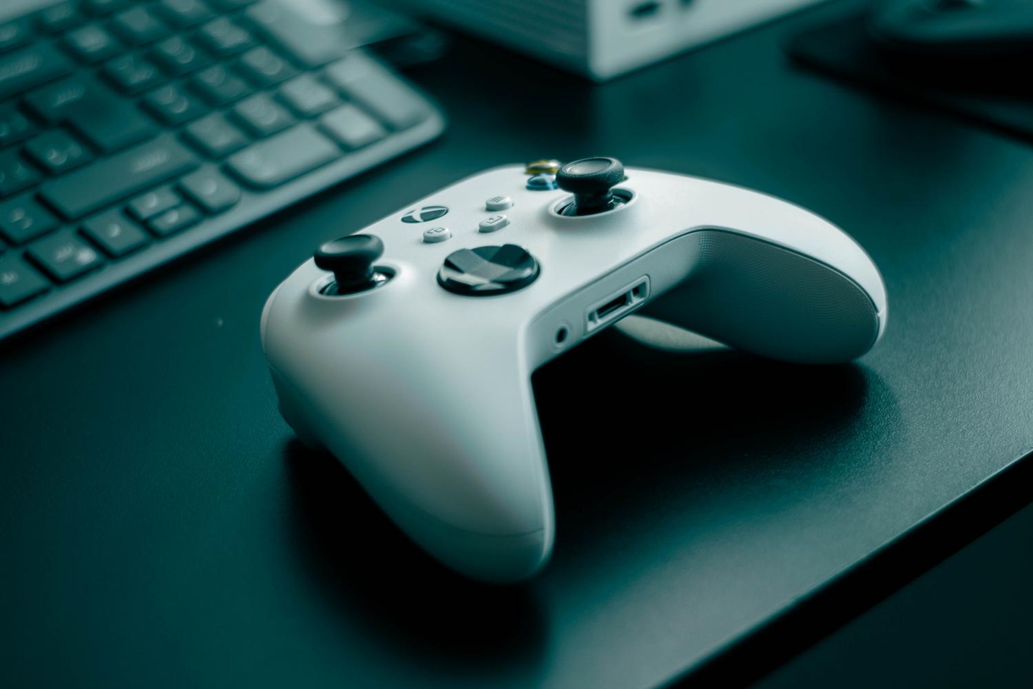 Primer plano de un mando de Xbox blanco sobre un escritorio moderno, ideal para ilustrar las ofertas de juegos digitales.