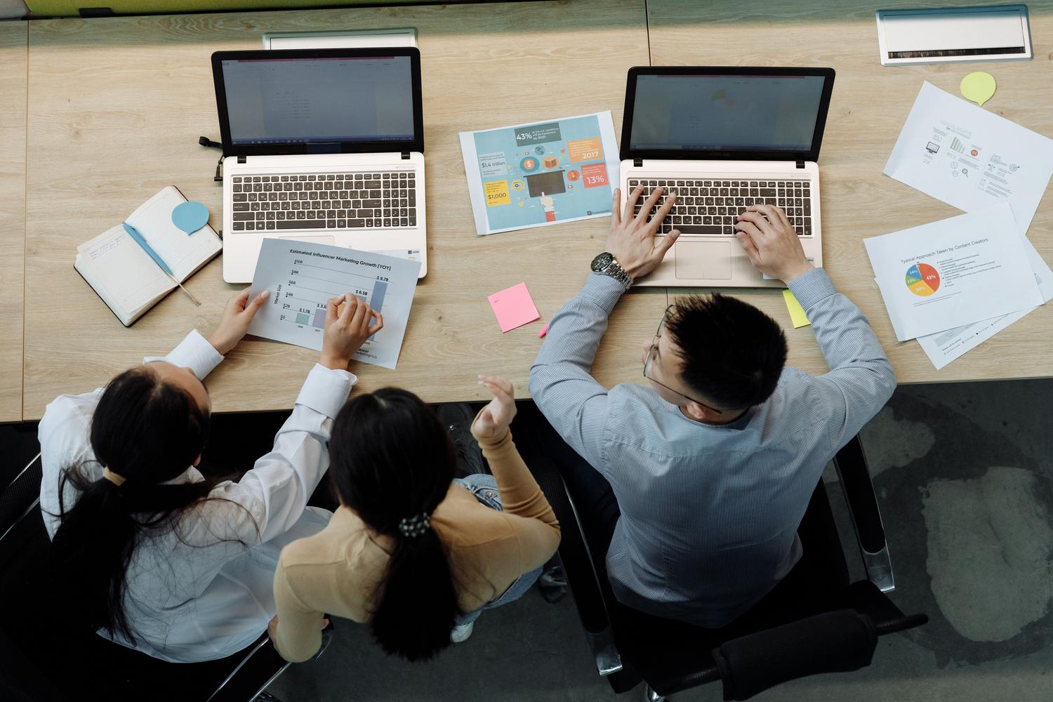 Equipo de trabajo consultando documentos y ordenadores portátiles.