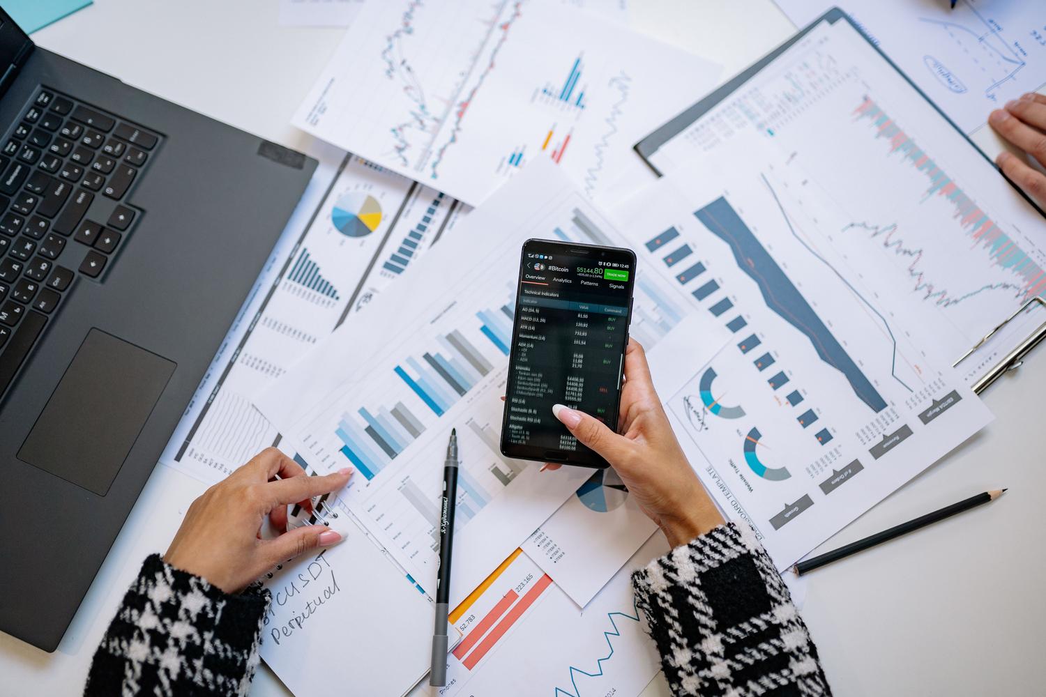 Overhead view of a desktop with a smartphone and data analysis charts.