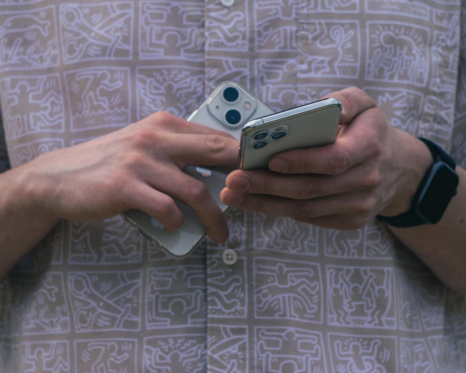 Persona sosteniendo dos smartphones, ilustrando la sincronización de fotos entre múltiples dispositivos