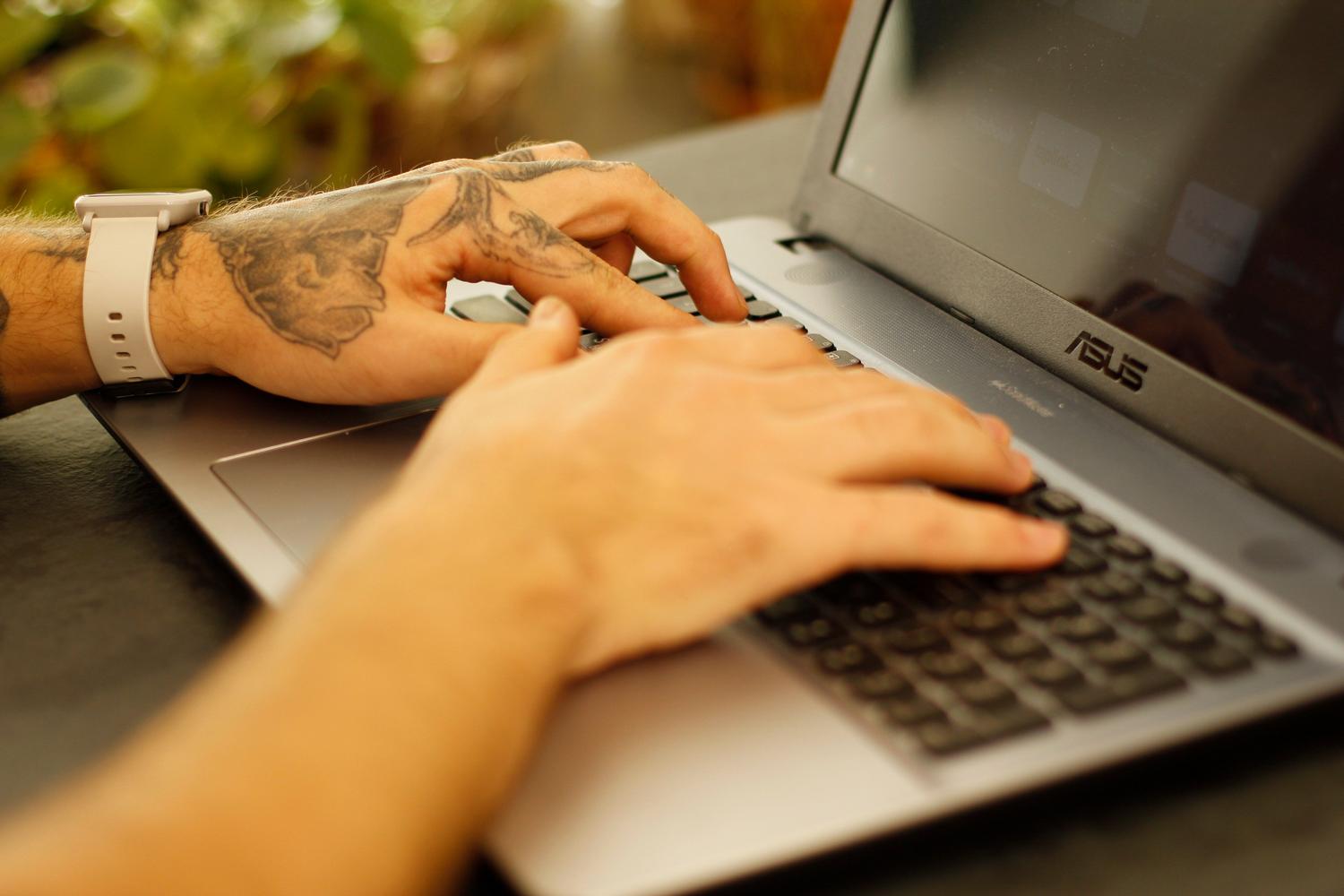 Detalle de manos escribiendo en un teclado de ordenador portátil, representando el uso de aplicaciones de notas en el escritorio.
