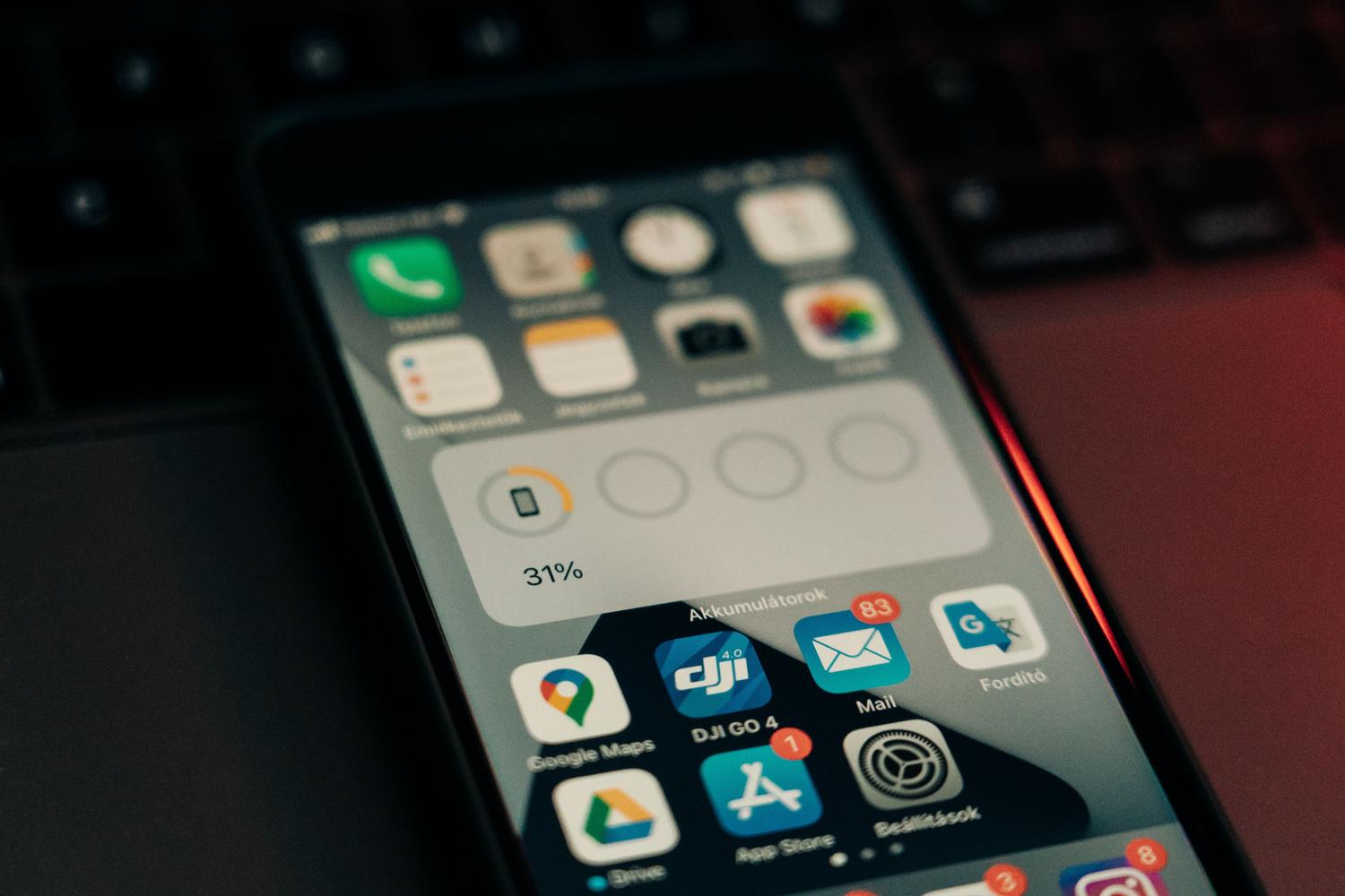 Primer plano de un smartphone mostrando el porcentaje de batería restante sobre un teclado, representando el monitoreo del consumo.