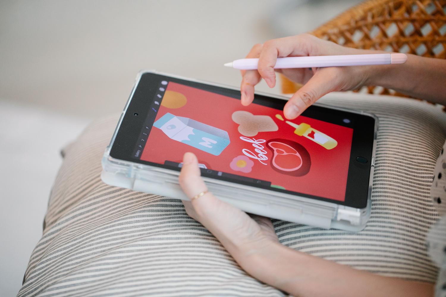 Manos utilizando una tableta y un lápiz para crear contenido visual.