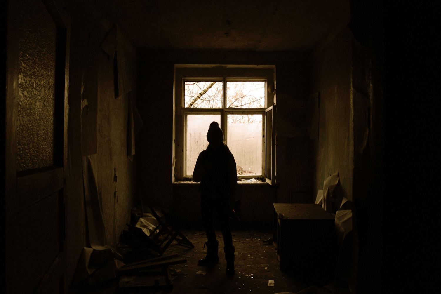 Silueta de una persona en una habitación abandonada y oscura, reflejando la atmósfera opresiva del terror psicológico.