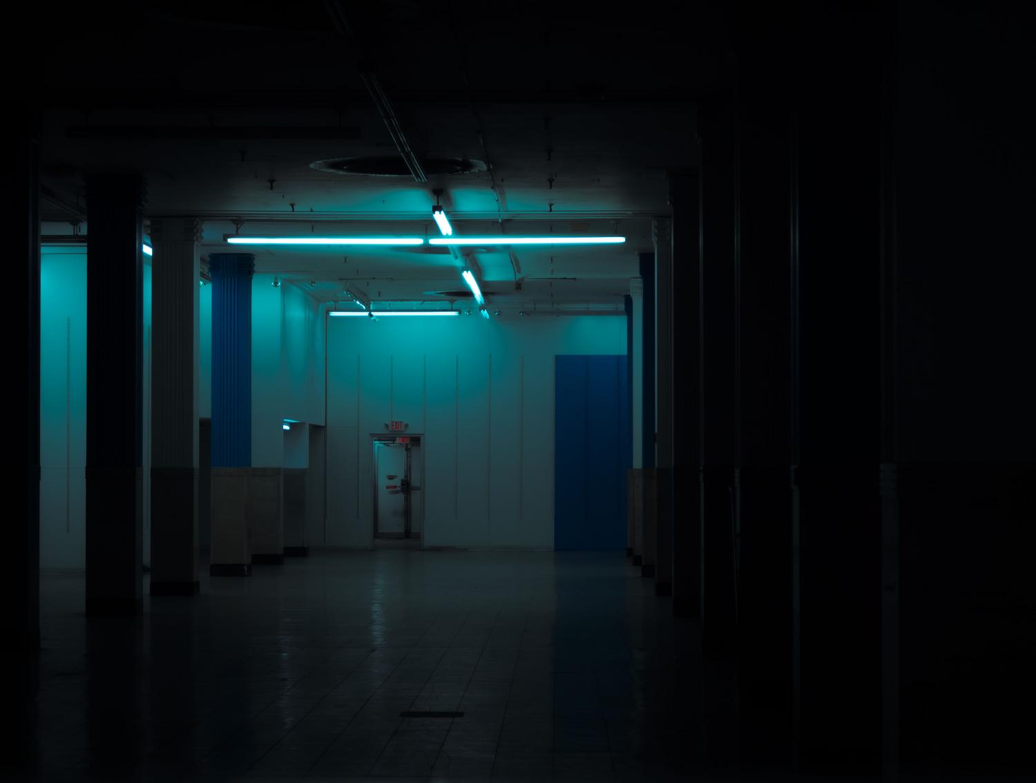 Corredor oscuro y misterioso con luz mínima, representando la angustia y el miedo de los juegos de supervivencia y escape.