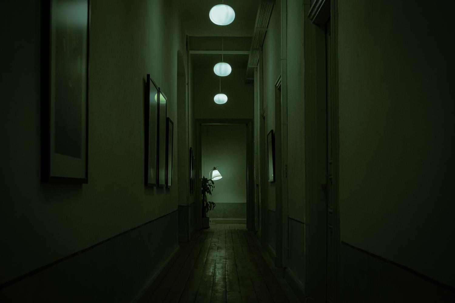 Pasillo oscuro y estrecho con iluminación verde inquietante, evocando la atmósfera de los juegos de survival horror.