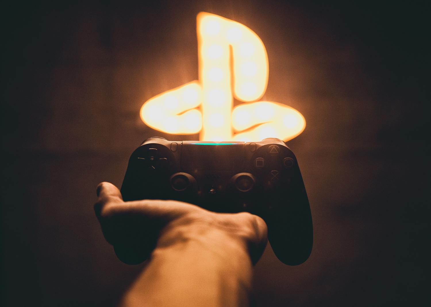 Gamer jugando con mando en una habitación oscura con iluminación neón, representando la atmósfera de jugar juegos de terror.