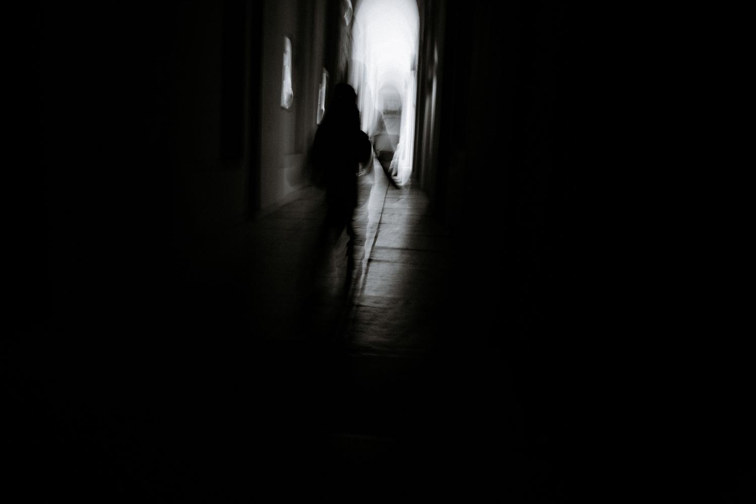 Silueta borrosa de una persona caminando por un pasillo oscuro y misterioso, capturando la tensión del horror psicológico y la angustia constante.