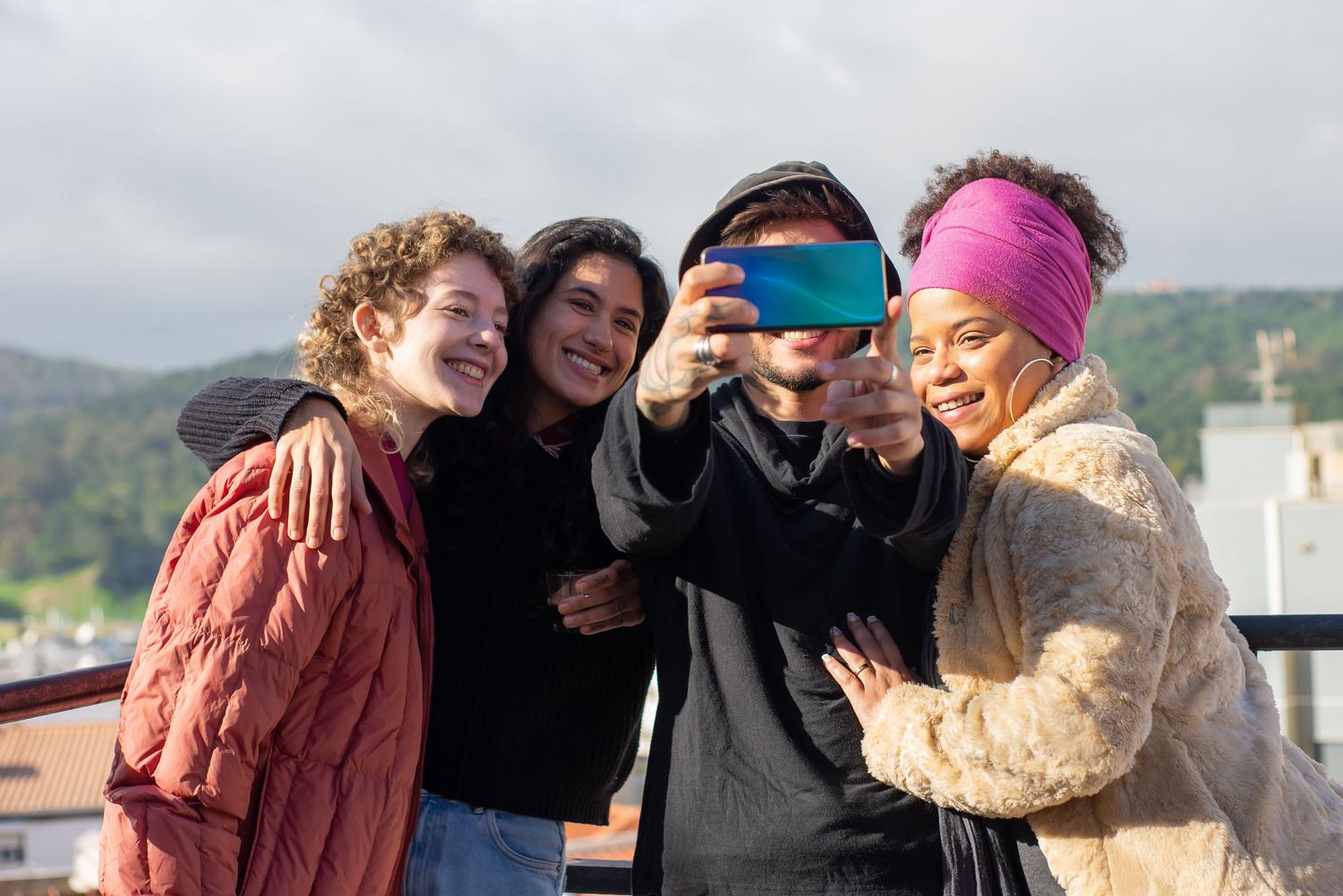 Grupo de amigos sonriendo mientras se toman una selfie, representando las funciones de toma grupal.