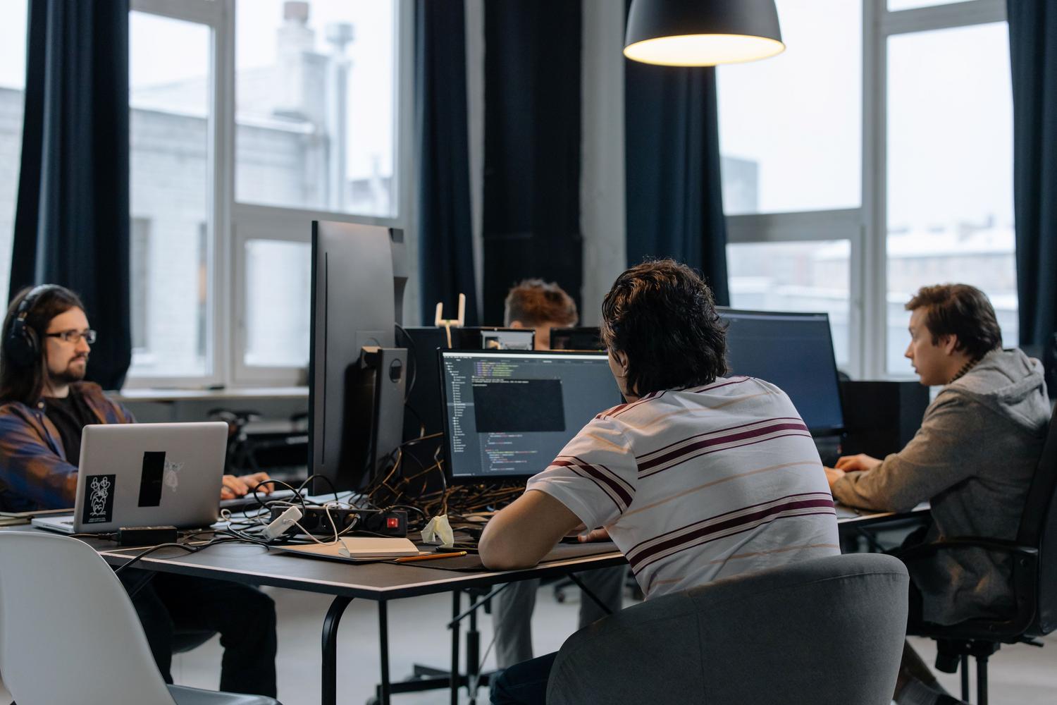 Equipo de profesionales tecnológicos trabajando en una oficina moderna, sugiriendo la búsqueda de soluciones técnicas