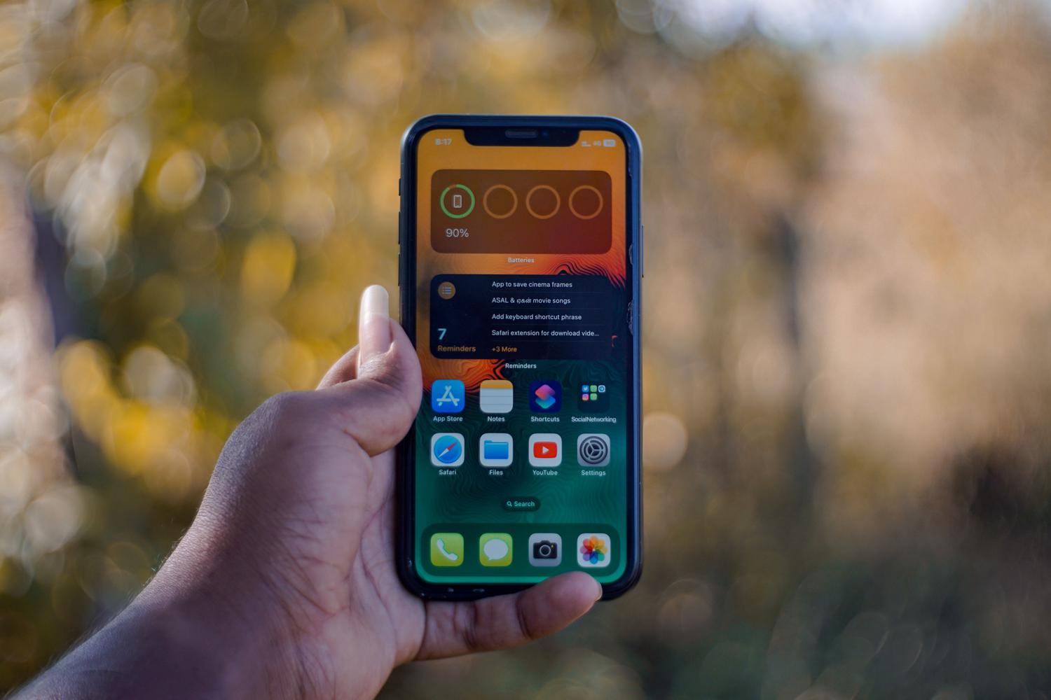 Mano sosteniendo un smartphone mostrando una cuadrícula de aplicaciones instaladas.