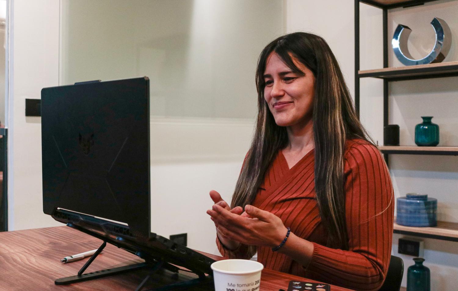 Mujer sonriendo durante una reunión virtual, representando una experiencia de usuario fluida y sencilla con herramientas de comunicación.