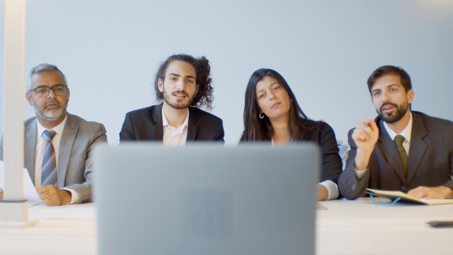 Equipo de profesionales en una reunión corporativa utilizando herramientas de videoconferencia en un entorno empresarial.