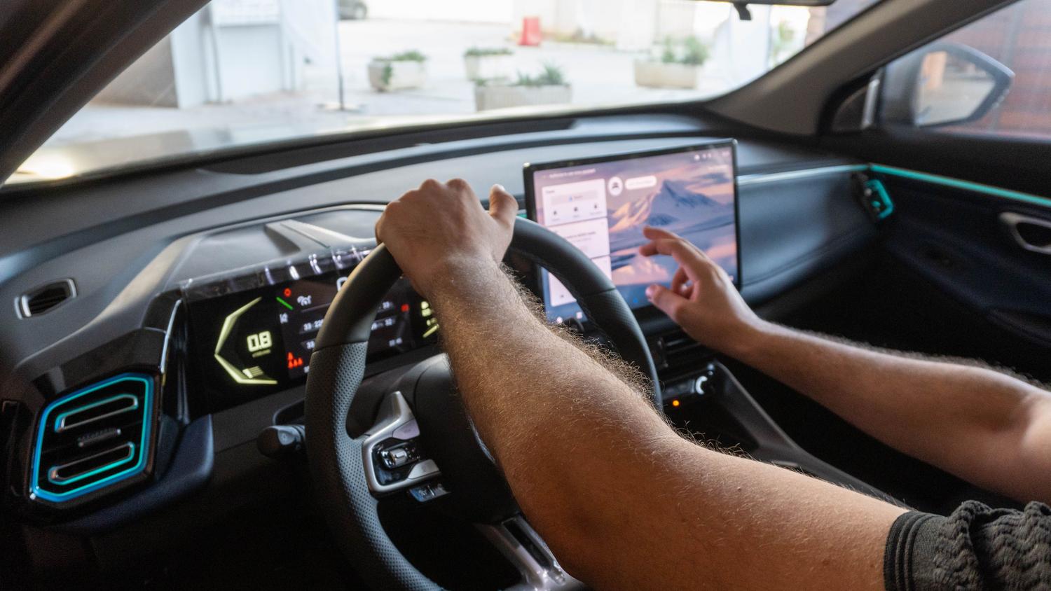 Conductor interactuando con la pantalla de infoentretenimiento de un coche moderno con interfaz tecnológica.