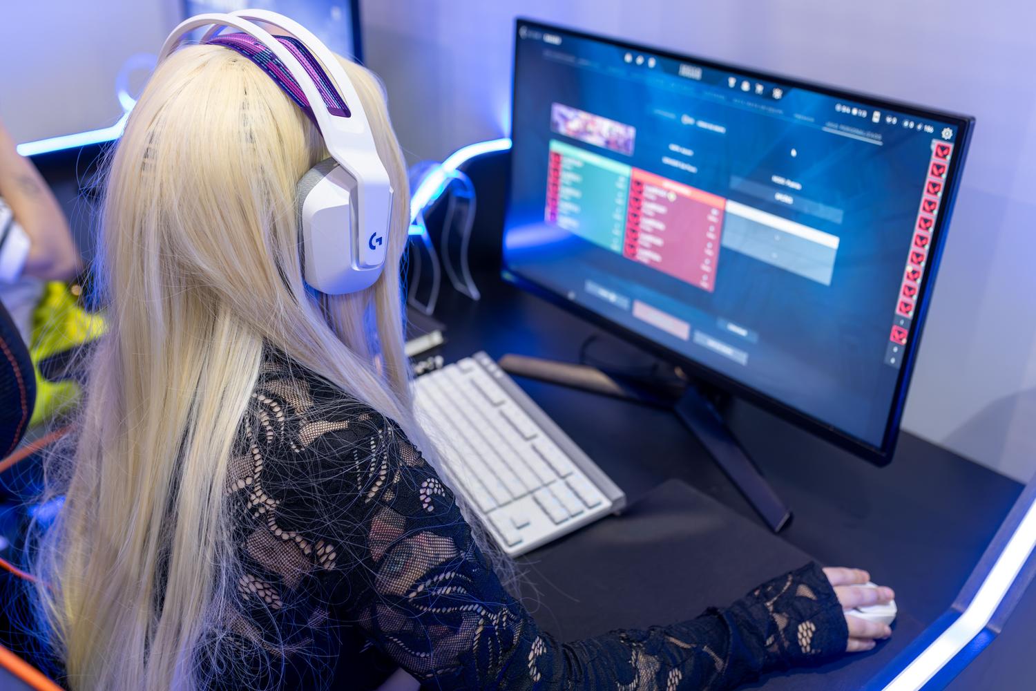 Joven jugadora concentrada frente a un setup de PC gaming avanzado con auriculares.