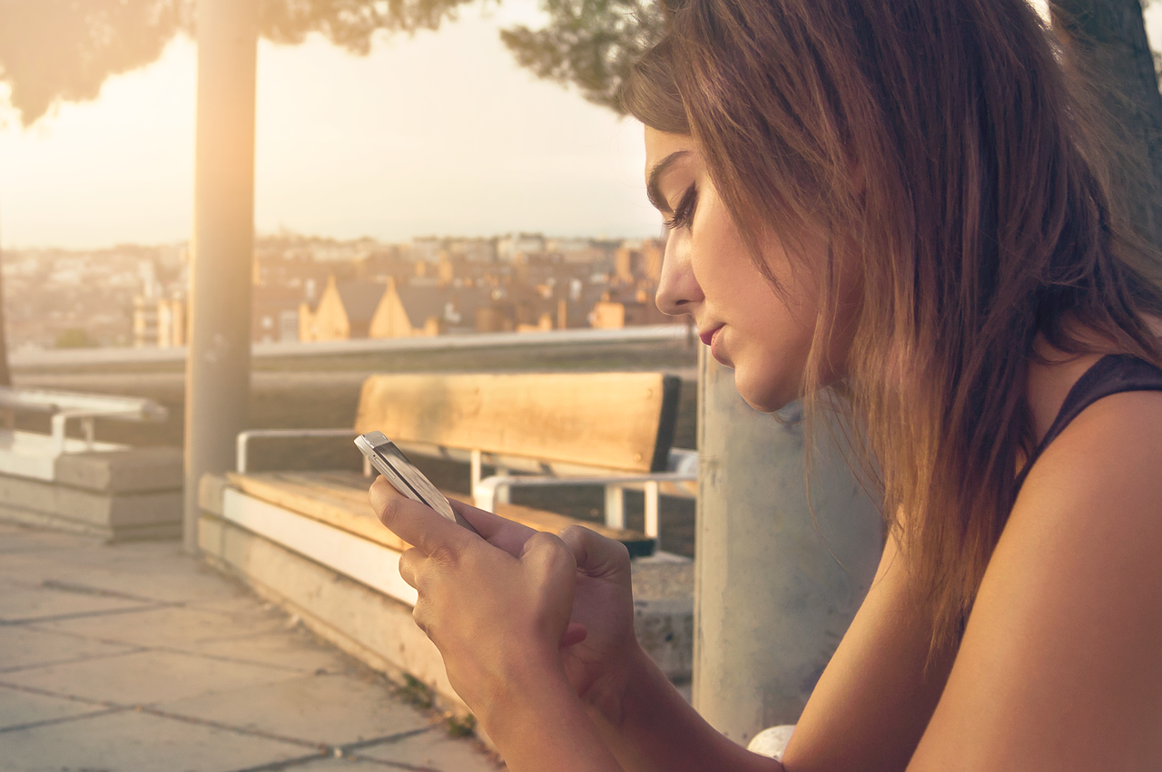 Mujer joven utilizando su teléfono móvil para comunicarse, representando el uso cotidiano de la mensajería.