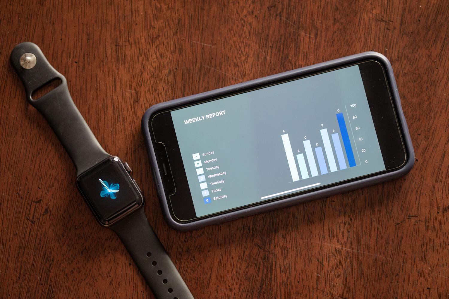 Un smartphone y un reloj inteligente sobre una mesa mostrando un reporte de salud, representando el ecosistema de análisis de Samsung Health.