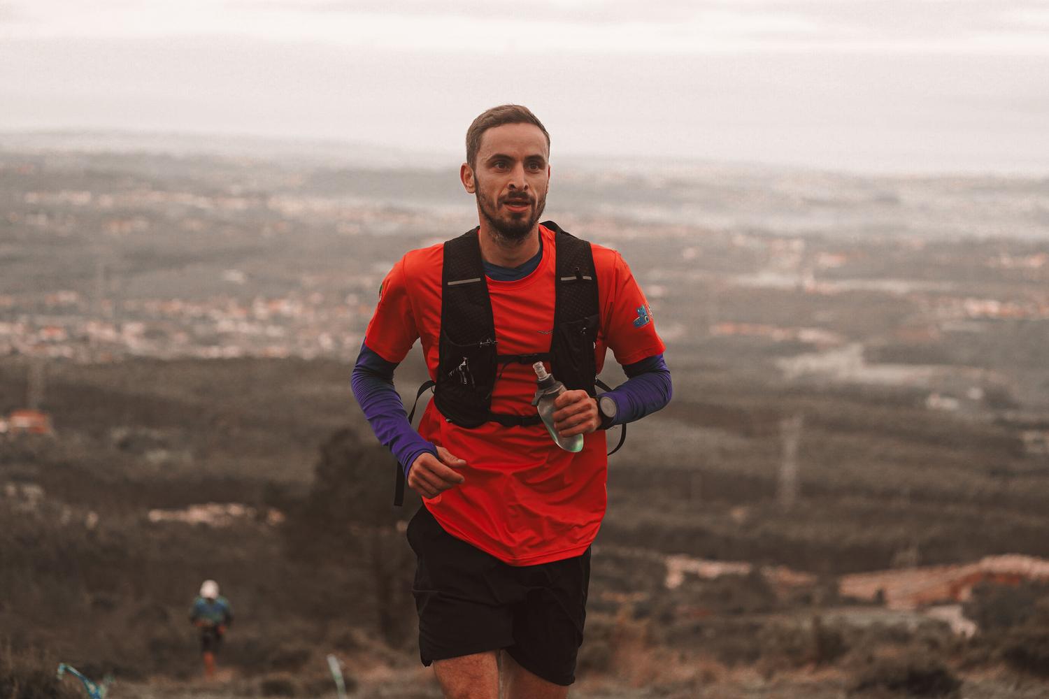 Hombre corriendo por un sendero de montaña, ilustrando las funciones de Running Coach y la integración con Strava.