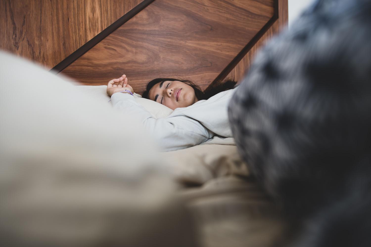 Mujer durmiendo plácidamente en una cama, ilustrando la importancia de un descanso reparador para obtener datos de sueño.