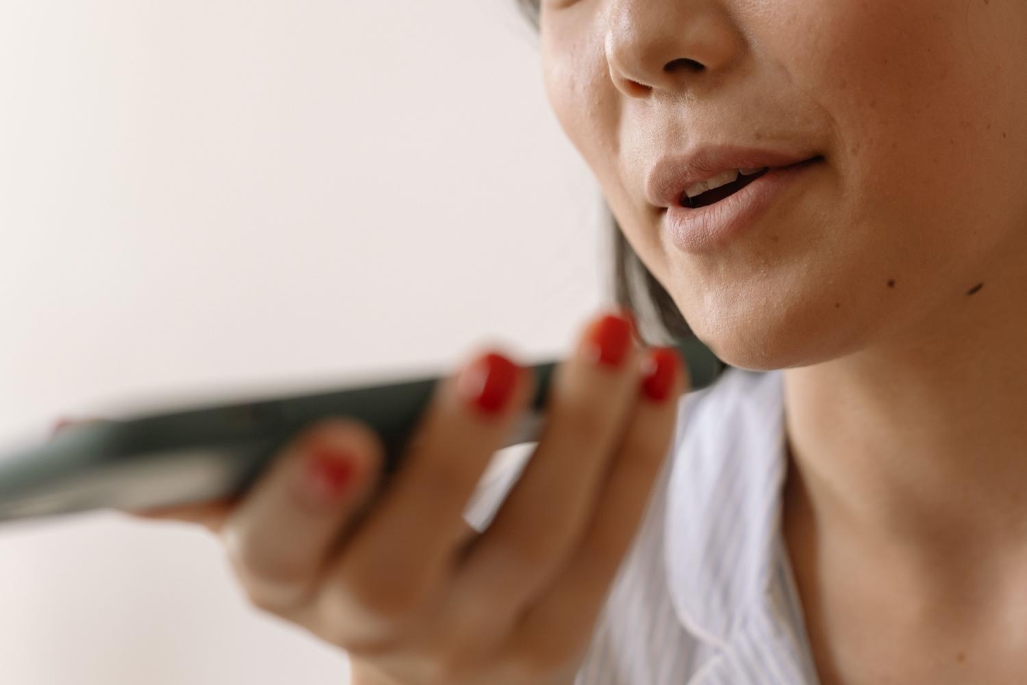 Vrouw spreekt dicht bij de microfoon van haar mobiele telefoon.
