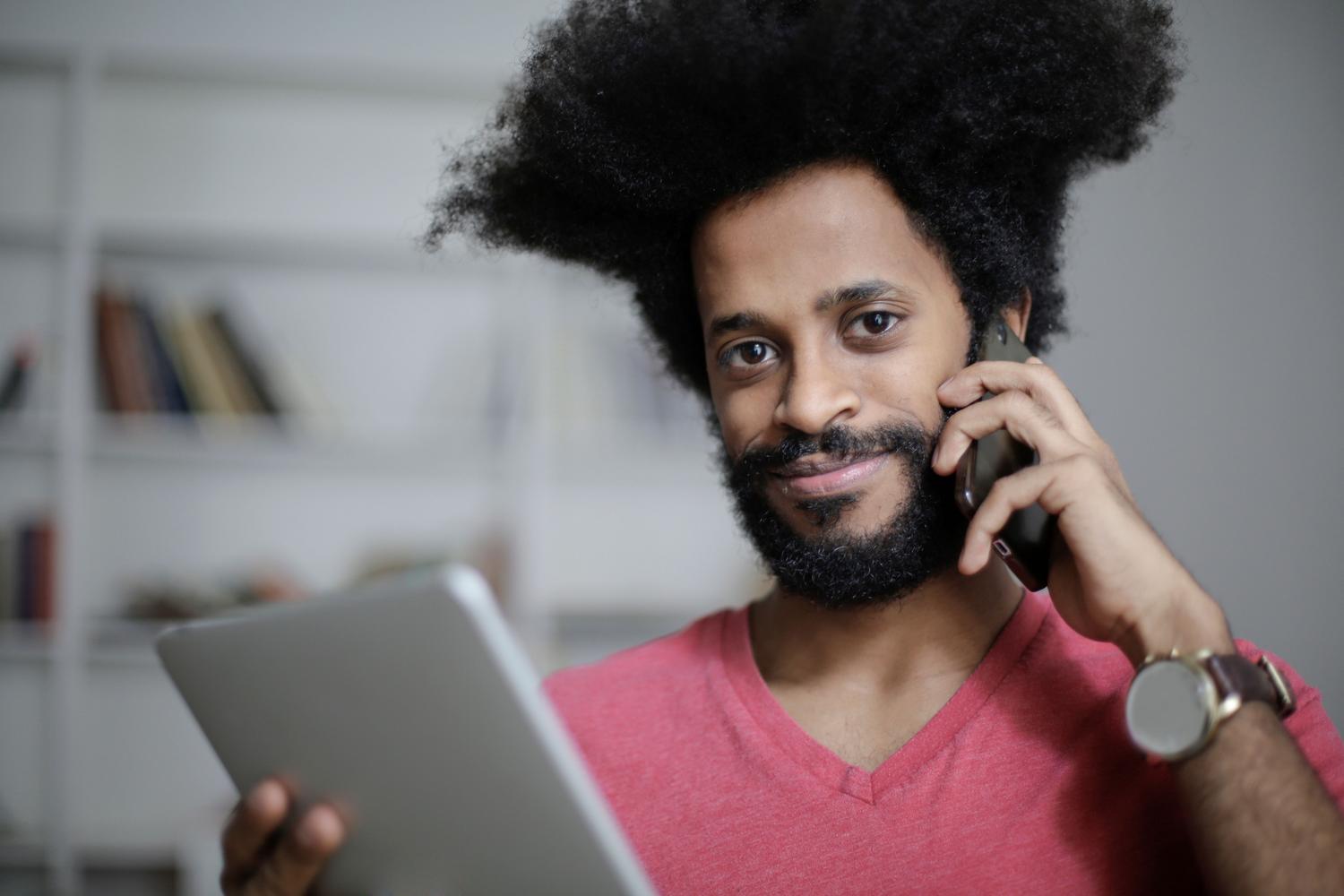 Hombre realizando una llamada telefónica mientras utiliza una tablet, ejemplificando el uso simultáneo de voz y datos gracias al VoLTE.
