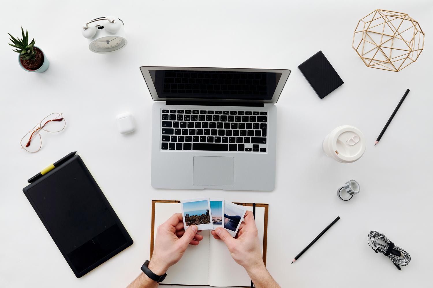 Organized workspace with laptop and printed photos, ideal for illustrating digital library management