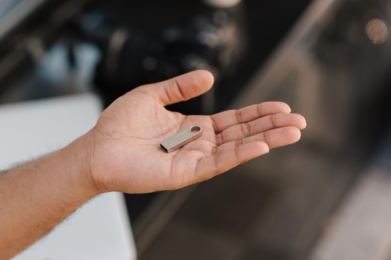 Persona sosteniendo un dispositivo de memoria USB portátil en la palma de la mano