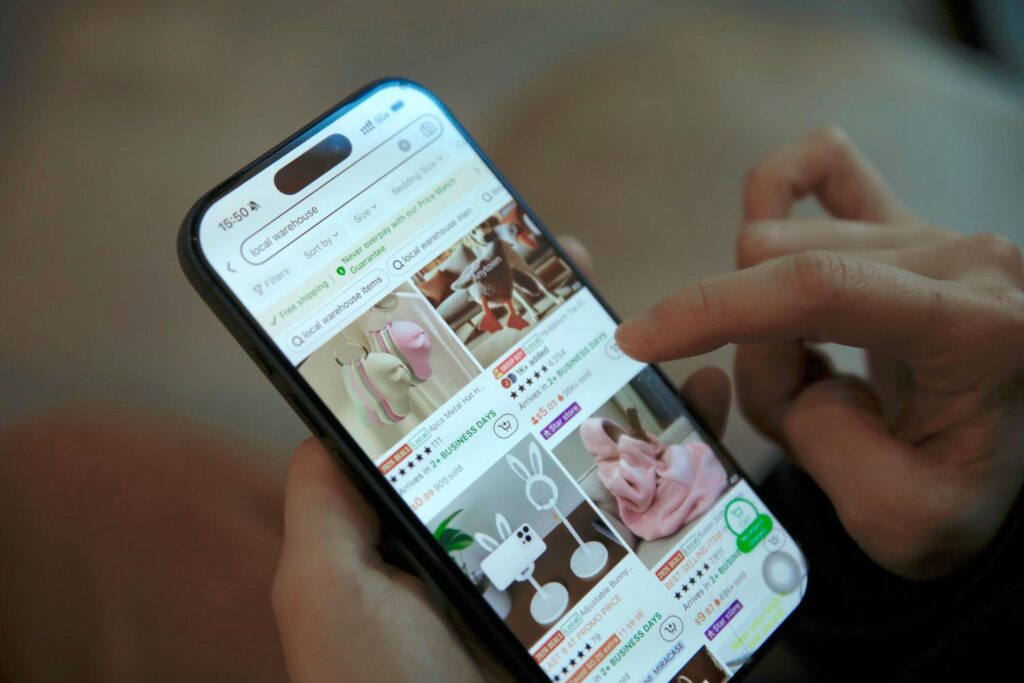 Osoba prohlíží nákupní aplikaci na svém chytrém telefonu a hledá produkty.