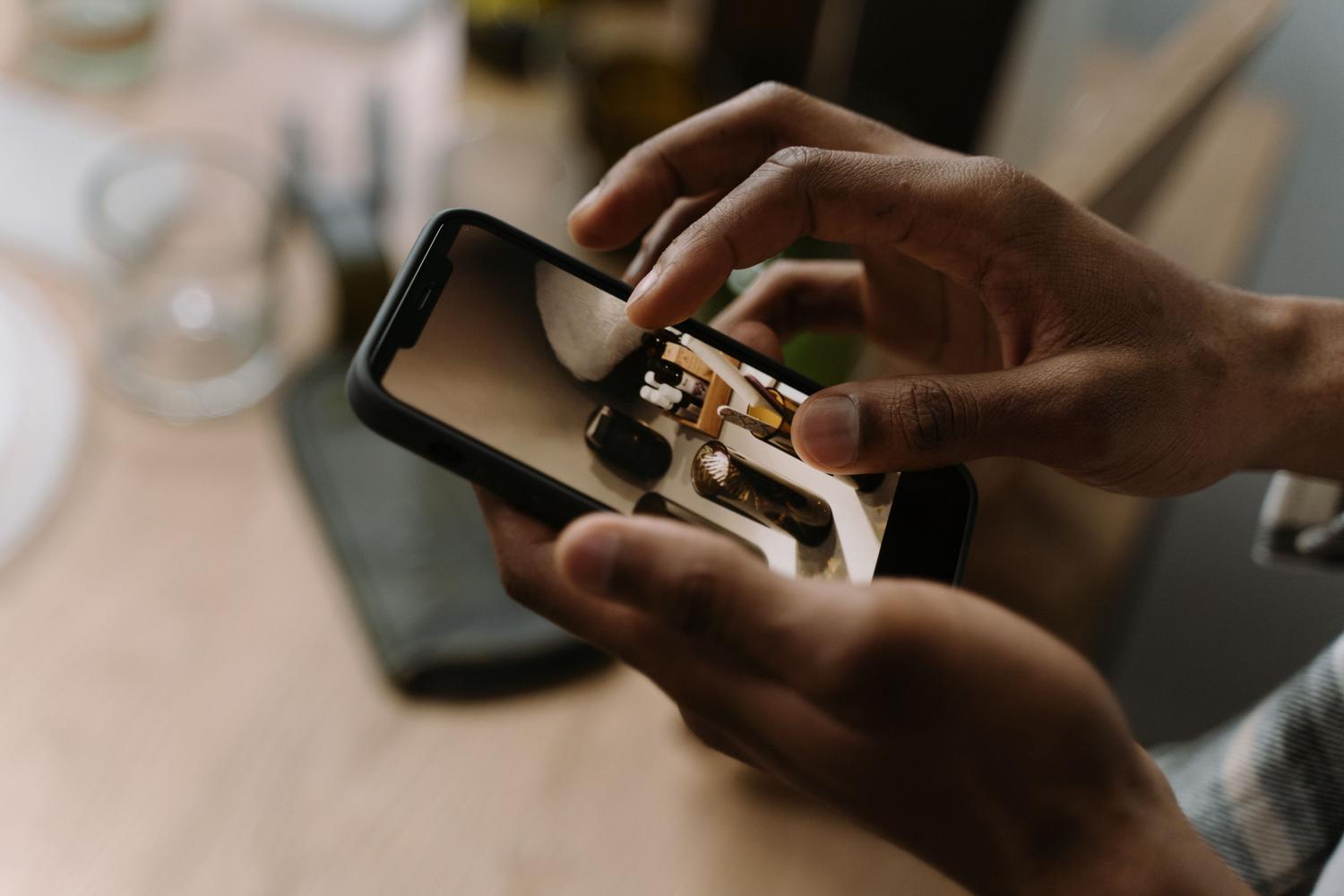 Roke držijo mobilni telefon med ogledovanjem slike na zaslonu za retuširanje.