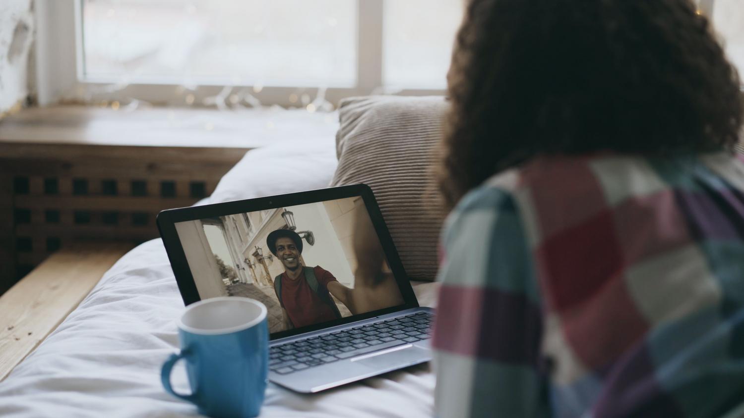 Mujer participando en una videollamada desde un ordenador portátil.