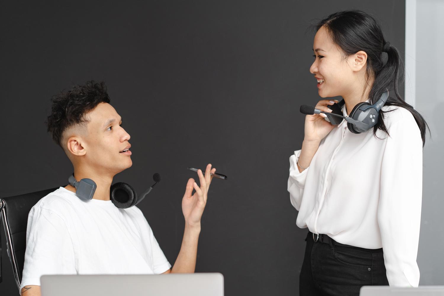 Dos colegas con auriculares conversando en una oficina moderna, representando la comunicación profesional a través de Google Chat.