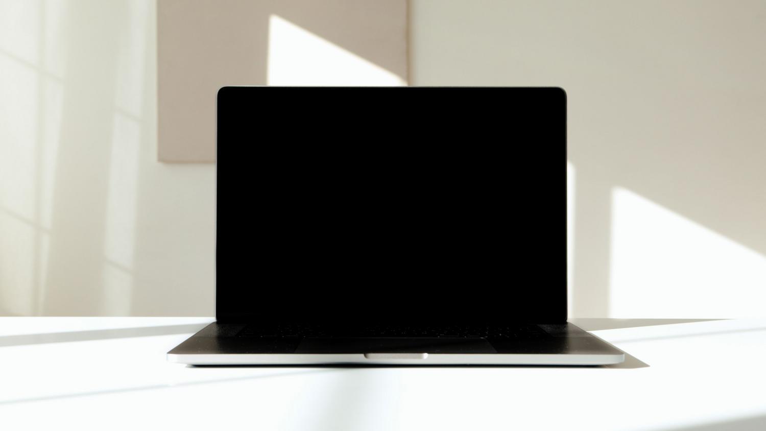 Portátil con la pantalla negra sobre un escritorio blanco
