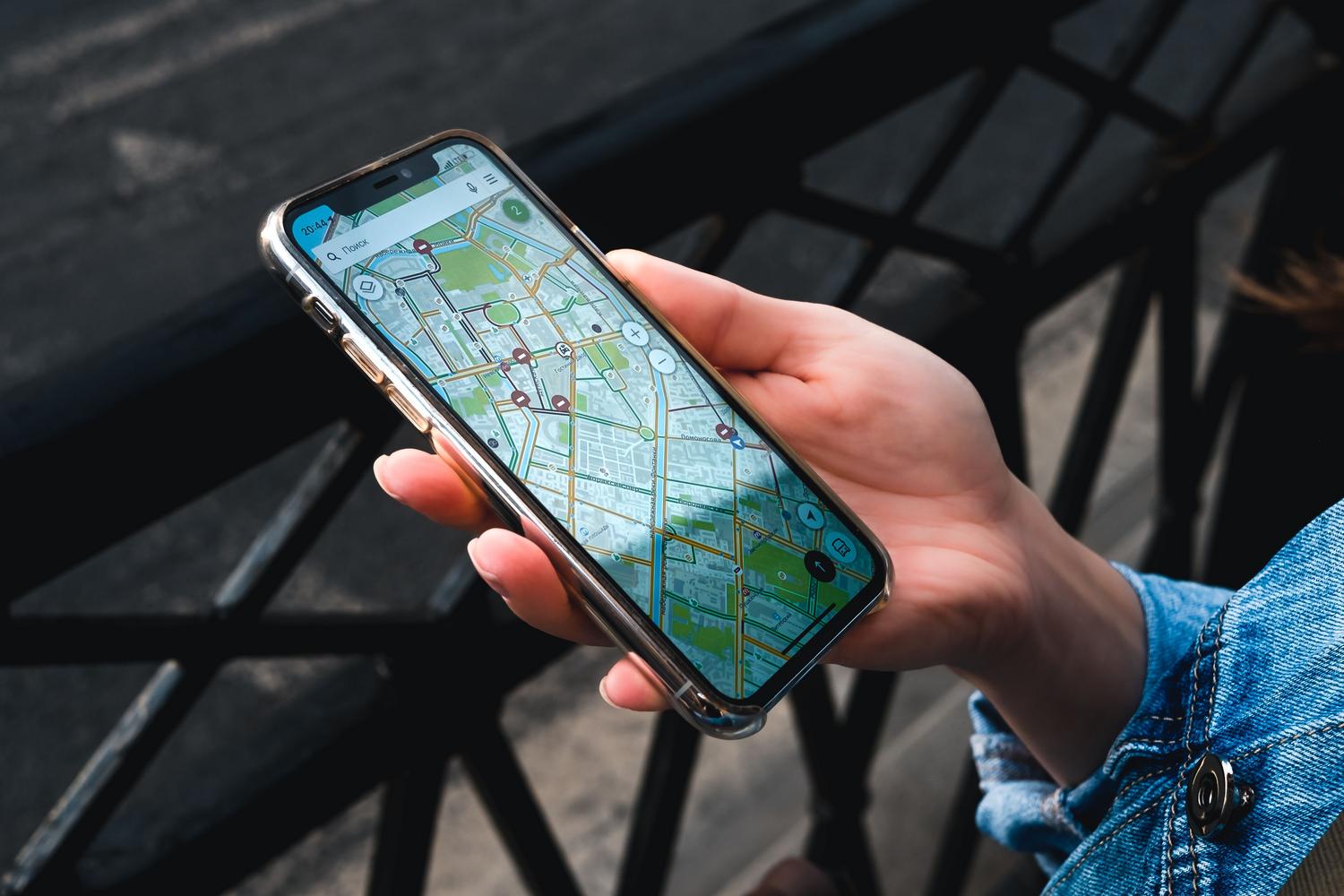 Primer plano de una mano sosteniendo un smartphone con una aplicación de mapas, representando la geolocalización.