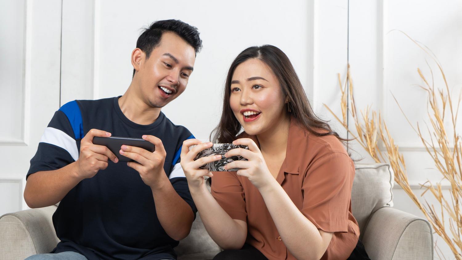 Dos personas disfrutando de juegos móviles en el sofá