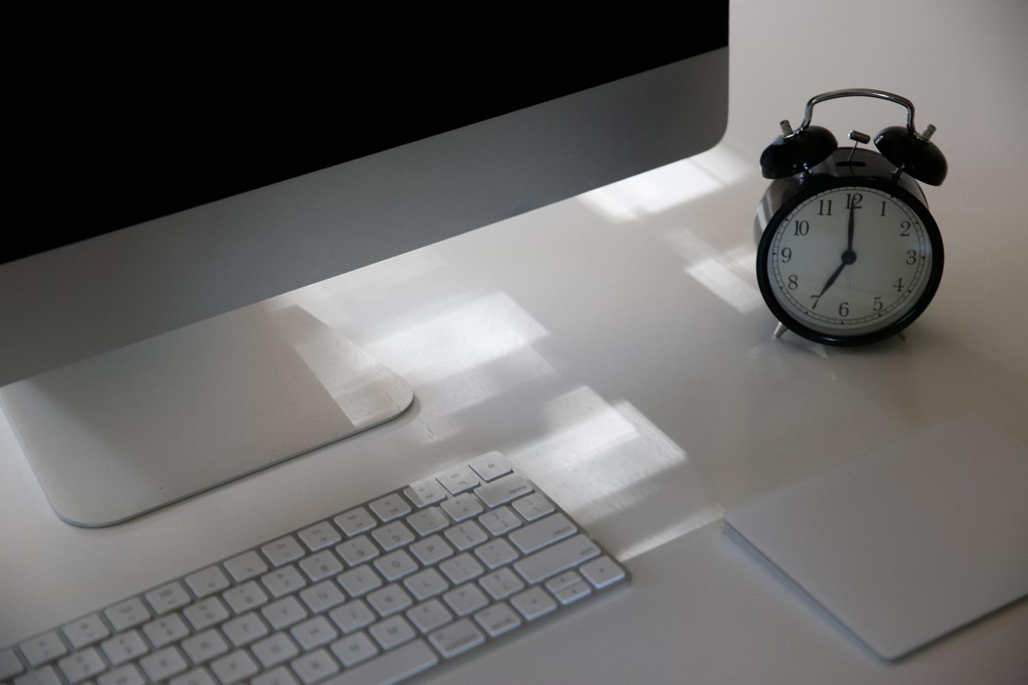 Teclado y reloj analógico sobre un escritorio.