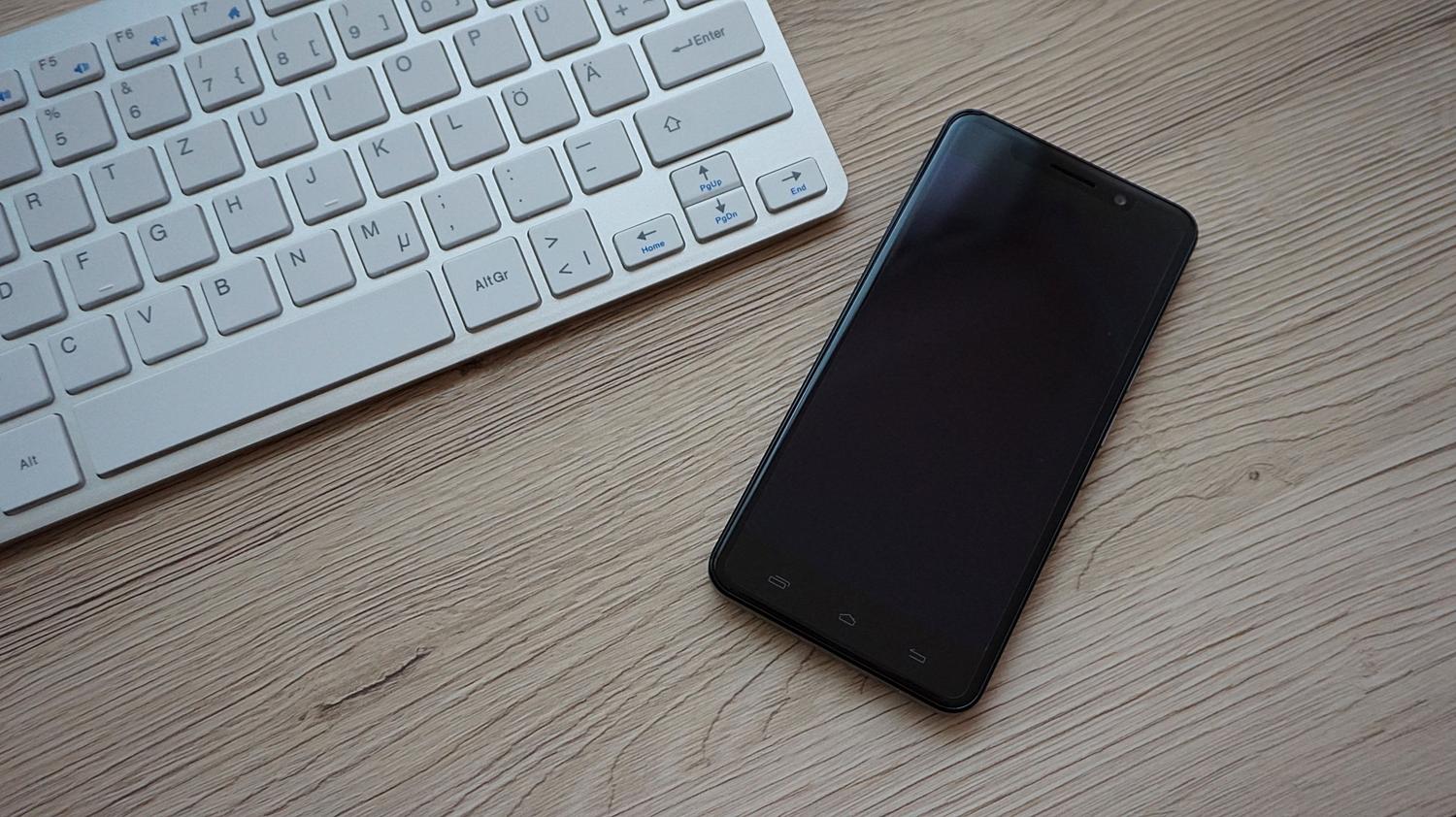 Teléfono móvil sobre un escritorio junto a un teclado físico.