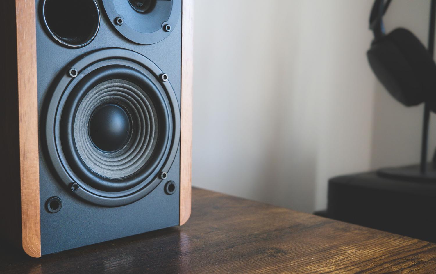 Primer plano de altavoces y auriculares sobre un escritorio, ilustrando el hardware de sonido.