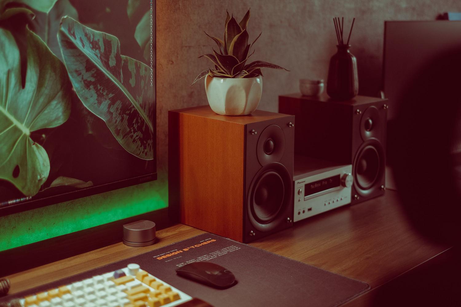 Setup de escritorio moderno con monitor y altavoces de madera, proporcionando un contexto de entorno de audio.