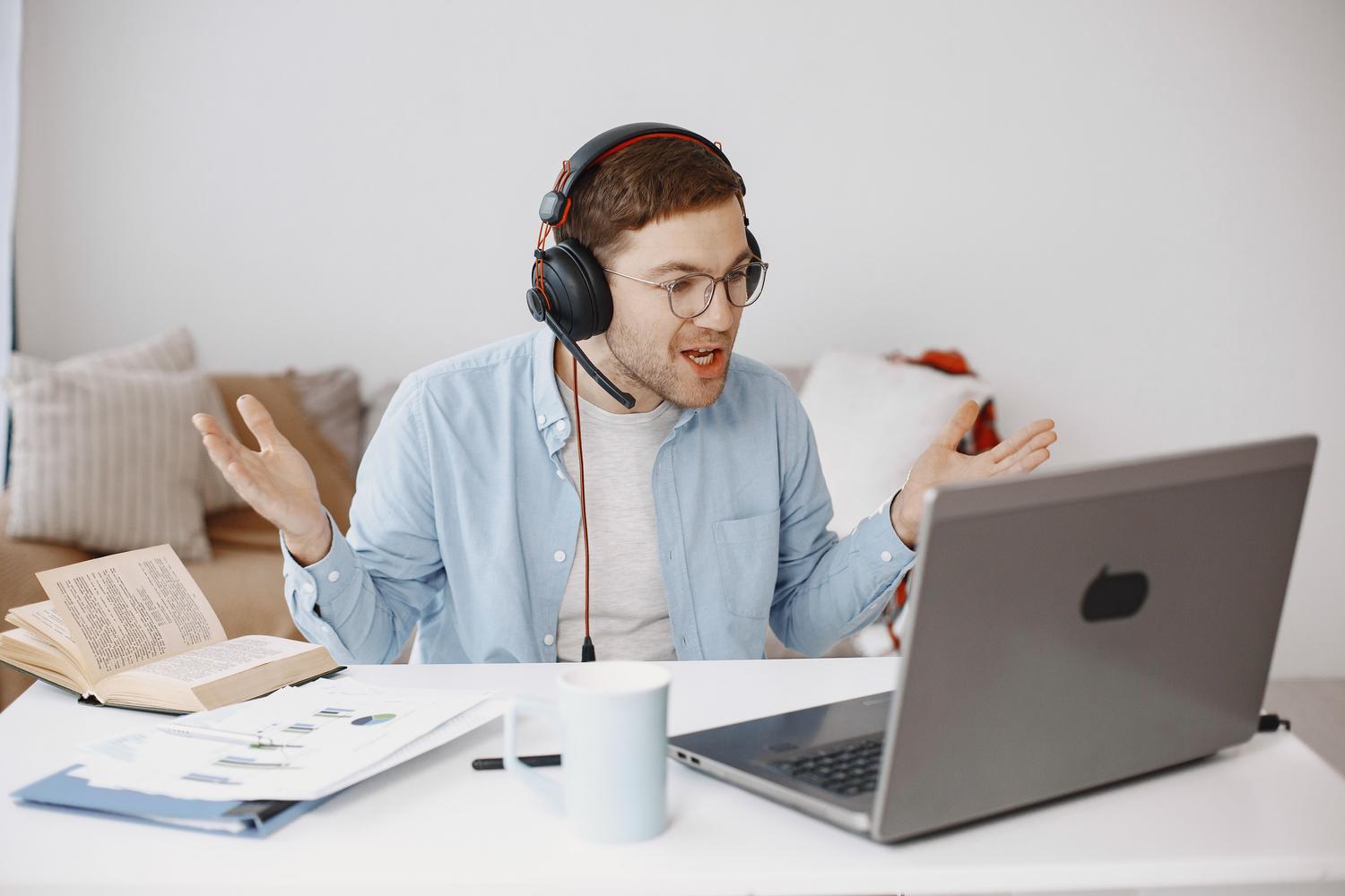 Persona exasperada con auriculares frente a un ordenador portátil, representando la frustración por fallos de audio.