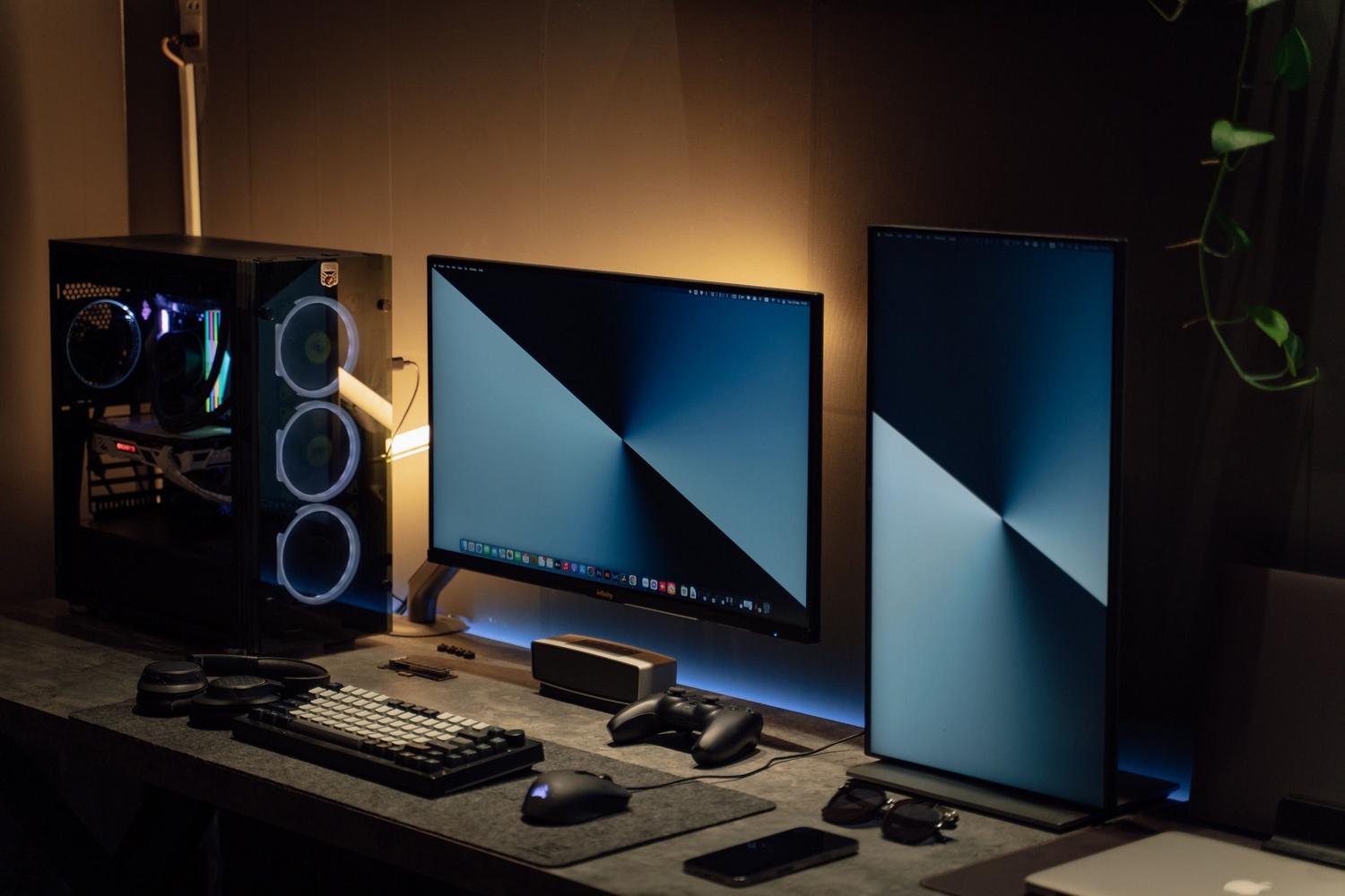 Configuración de escritorio moderna con doble monitor y gadgets tecnológicos, representando un entorno profesional para el desarrollo de agentes de IA.